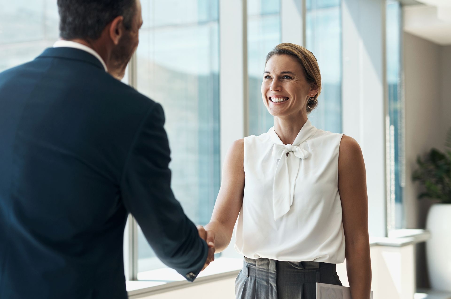 A smiling employee shakes hands with a professional in a business suit, symbolizing a successful resolution of a wage dispute with legal assistance.