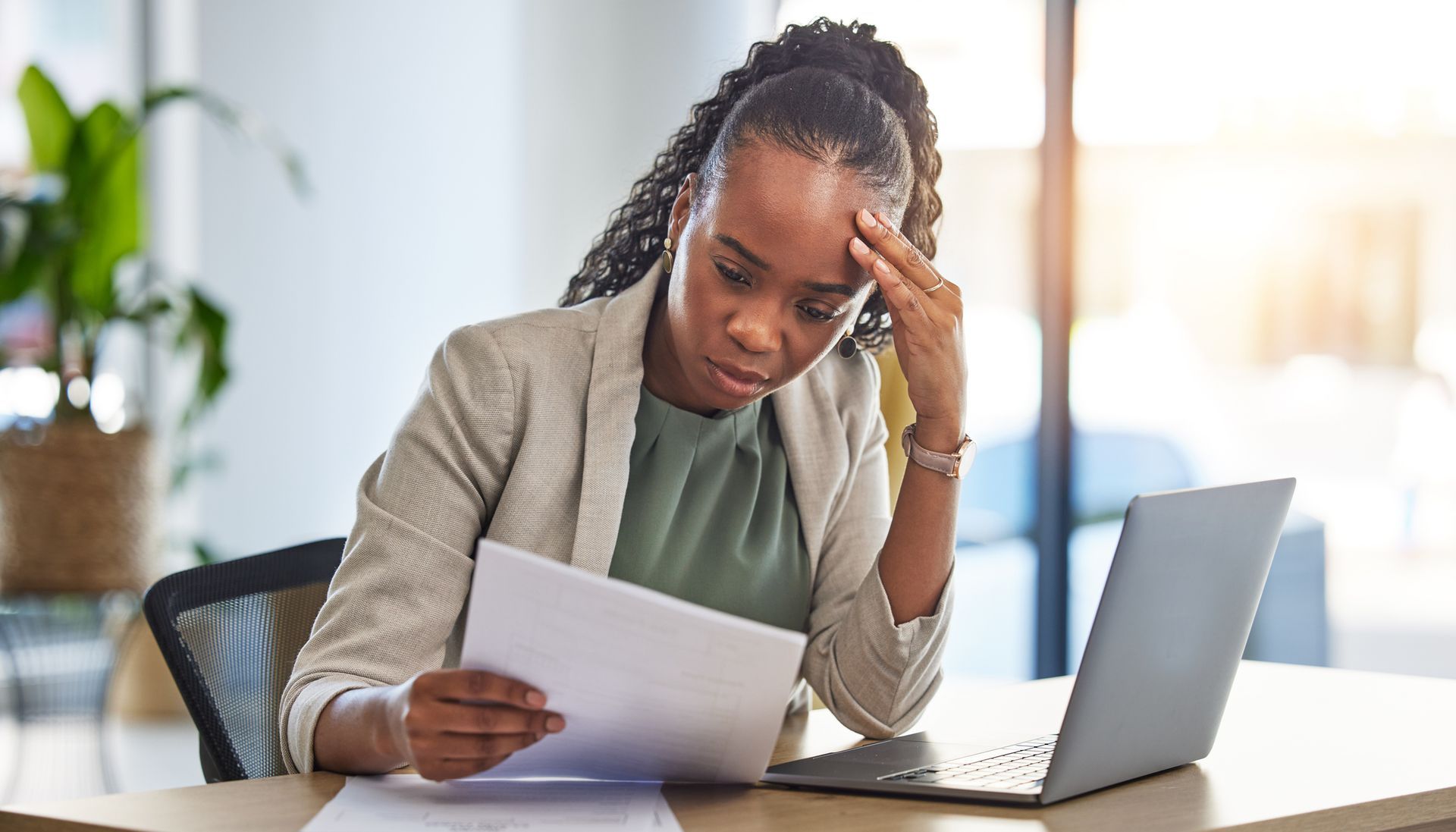 A concerned employee sits at a desk, reviewing a pay stub with a frustrated expression.