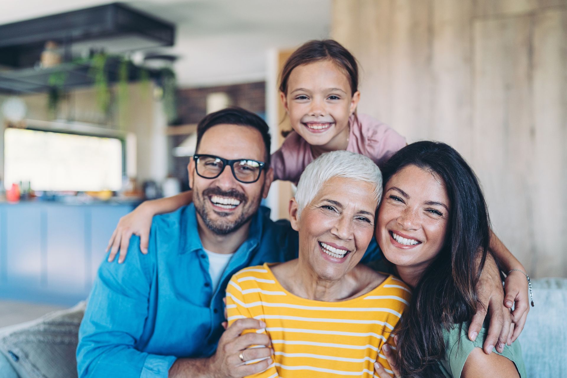 A cheerful family of four, including multiple generations, smiling in a cozy home setting, symbolizing the security life insurance offers.