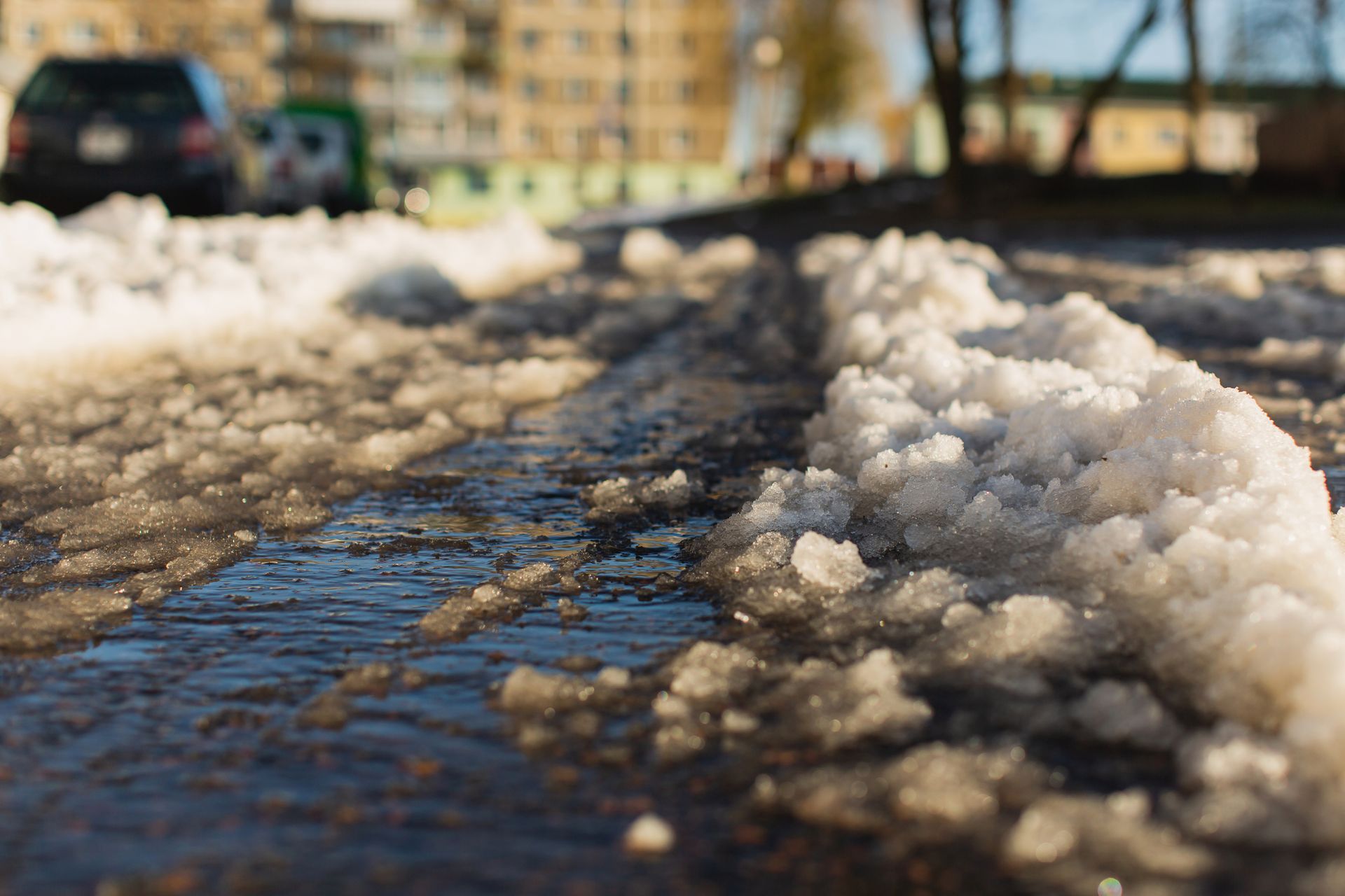Slushy, icy sidewalk in an urban area, showing dangerous winter conditions that could cause a slip and fall accident.