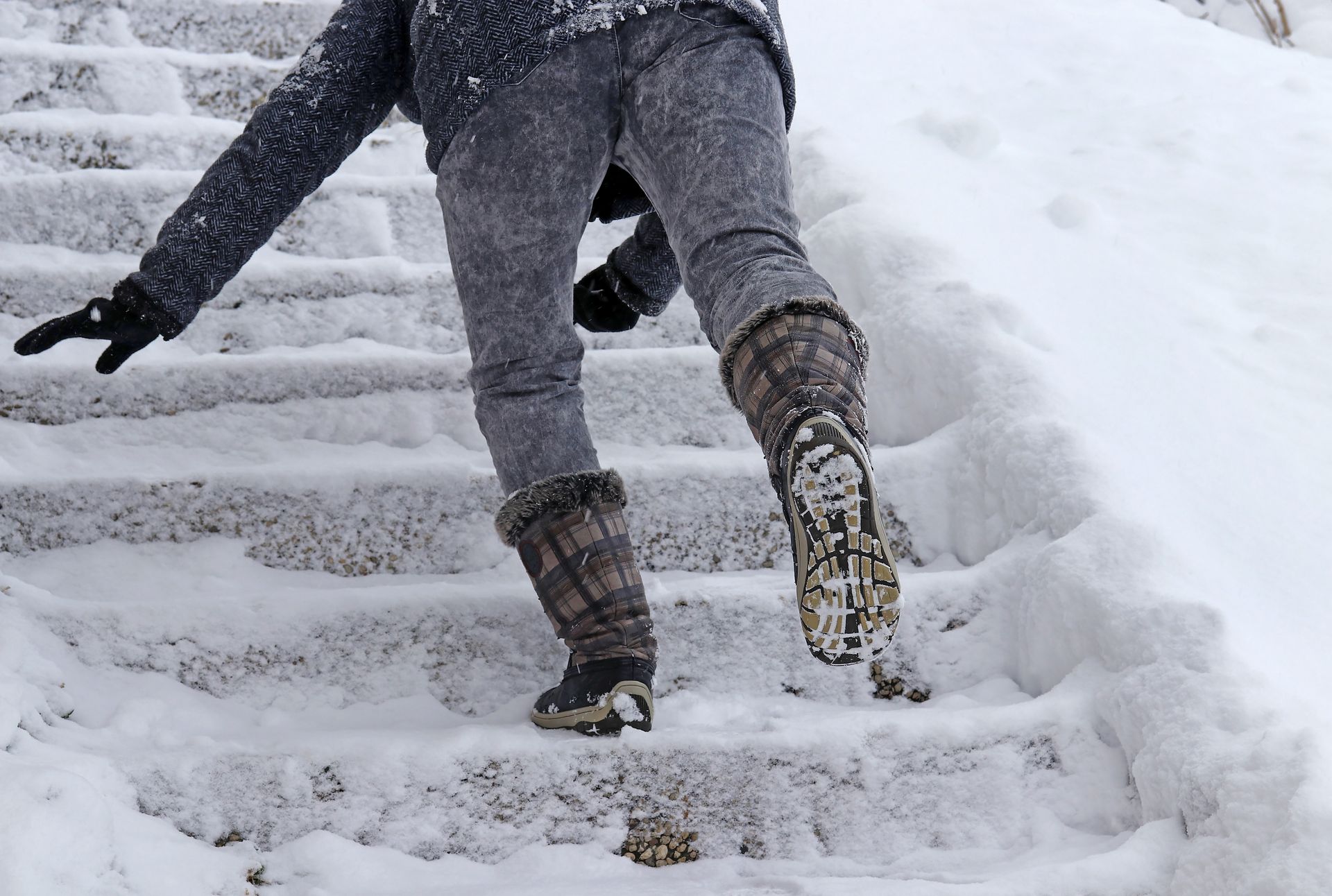 A person slipping on icy stairs, illustrating the hazards of unsafe conditions on private property during winter.