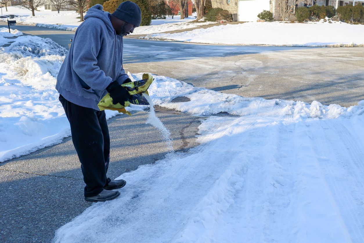 A man spreads salt on icy driveway to prevent slip and fall accidents during cold weather, helping to reduce the risk of an accident and a slip and fall injury lawsuit.