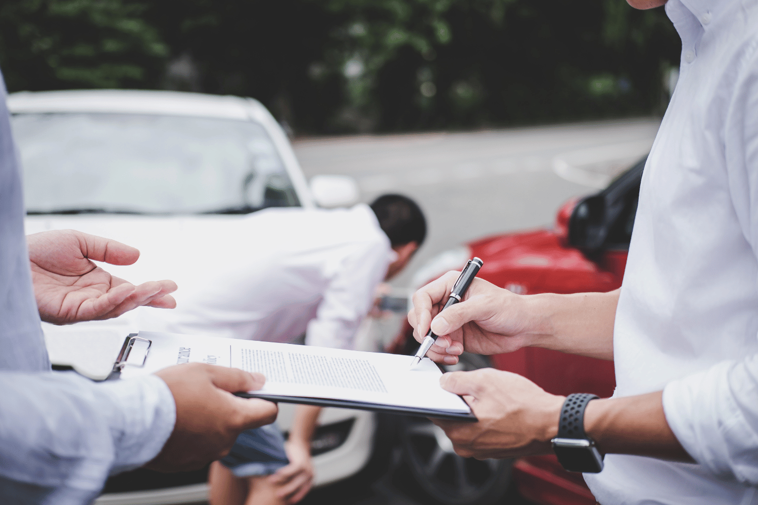People signing documents outdoors beside parked cars