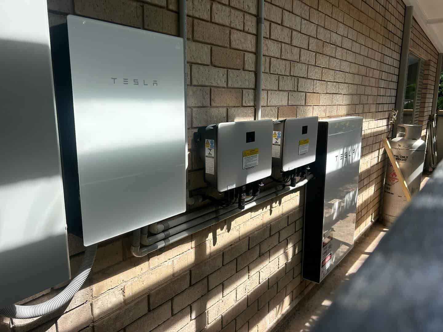A Row of Tesla Solar Panels Are Mounted on a Brick Wall — Eco Sparks Solar & Electrical Contractors in Palmerston, NT