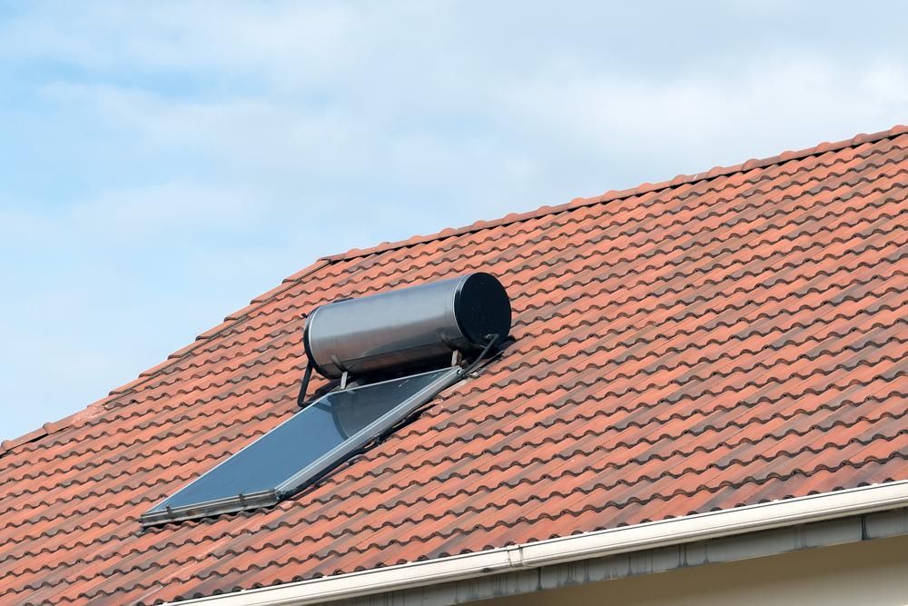 A Solar Water Heater Is Mounted On The Roof Of A House — Eco Sparks Solar & Electrical Contractors in Berrimah, NT