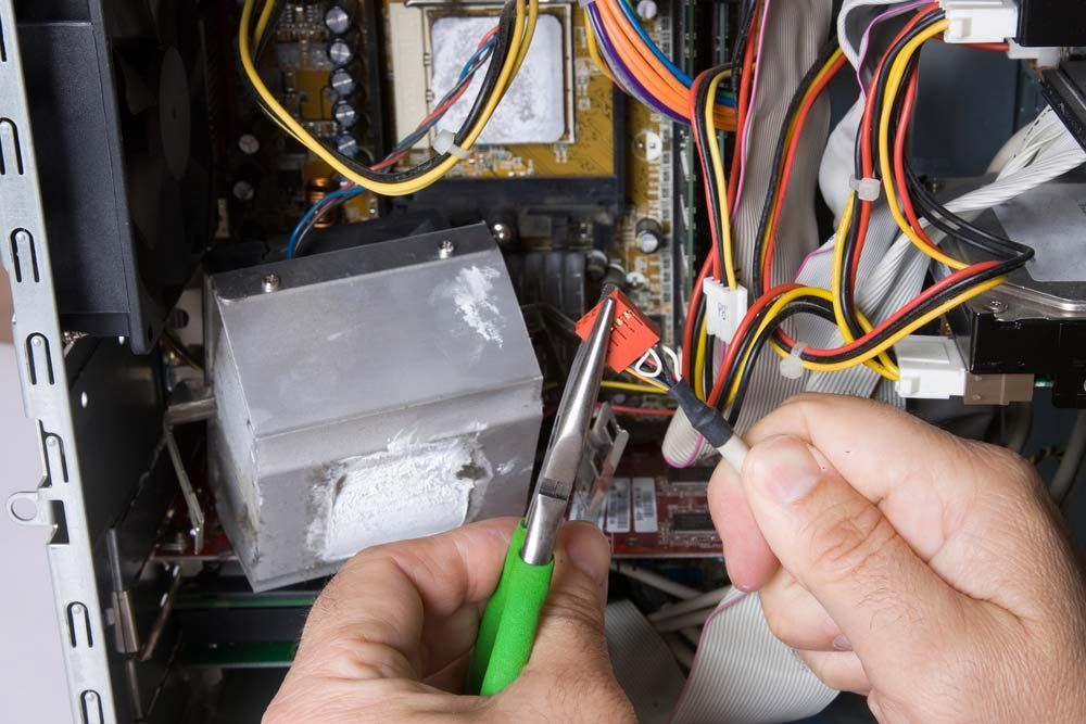 A Person is Working on a Computer With a Pair of Pliers — Eco Sparks Solar & Electrical Contractors in Rural Darwin, NT