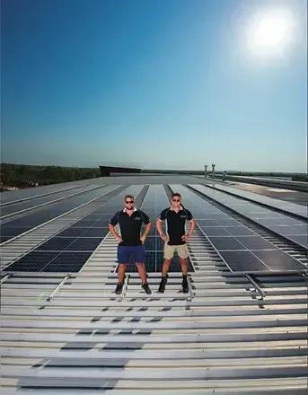 Two Men Are Standing on Top of A Roof with Solar Panels — Eco Sparks Solar & Electrical Contractors in Berrimah, NT