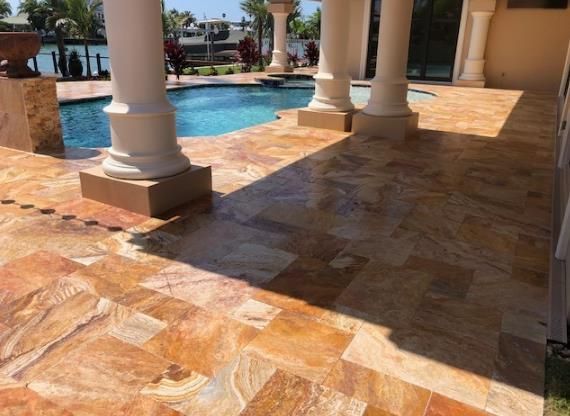 a patio with tiles and columns next to a pool .