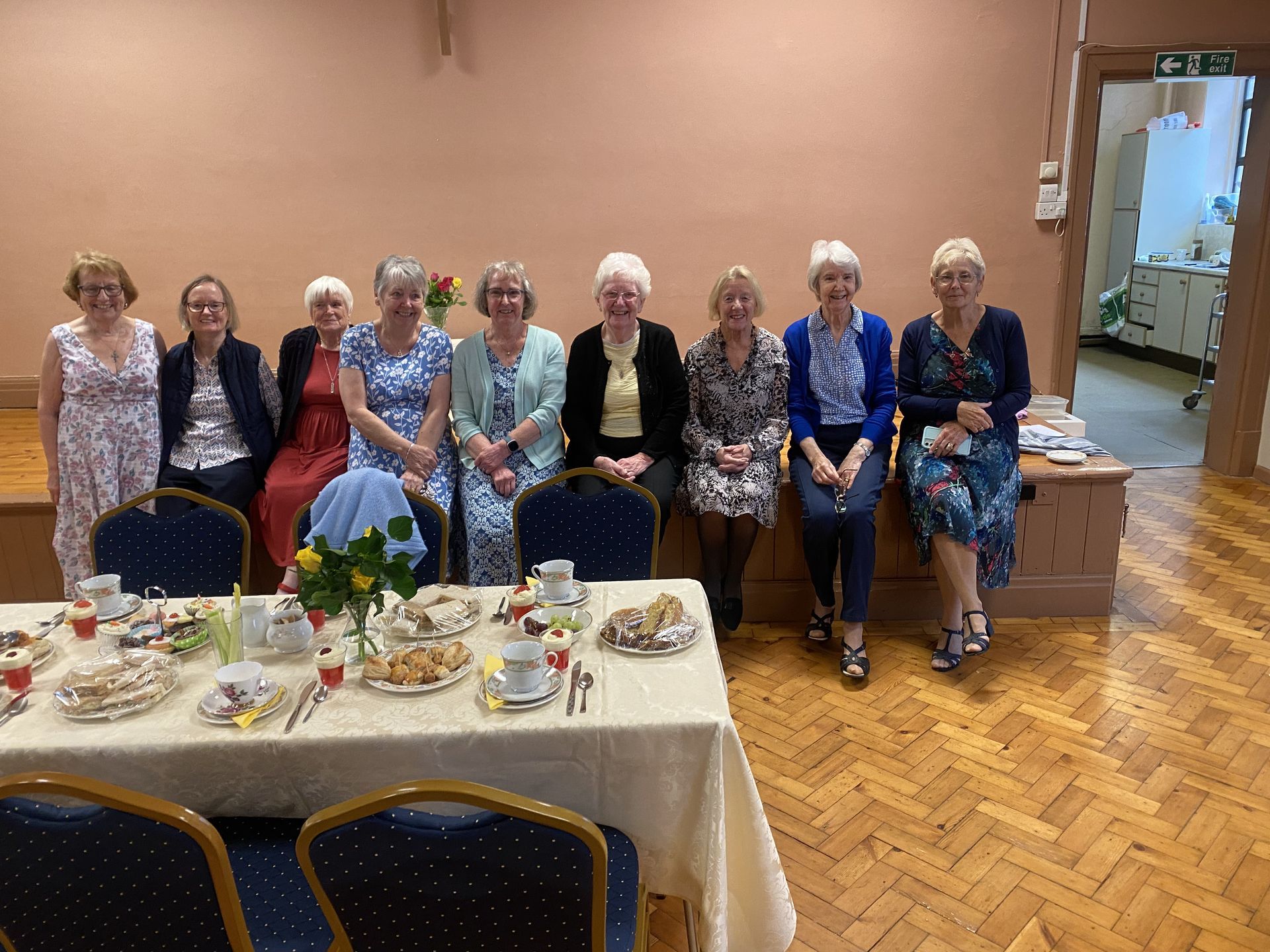 A group of women sitting around a table with plates of food on it