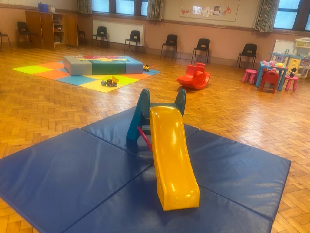 A yellow slide is sitting on a blue mat in a play room.