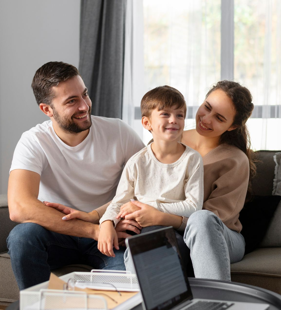 Family sitting on a couch, smiling and relaxed in a bright living room
