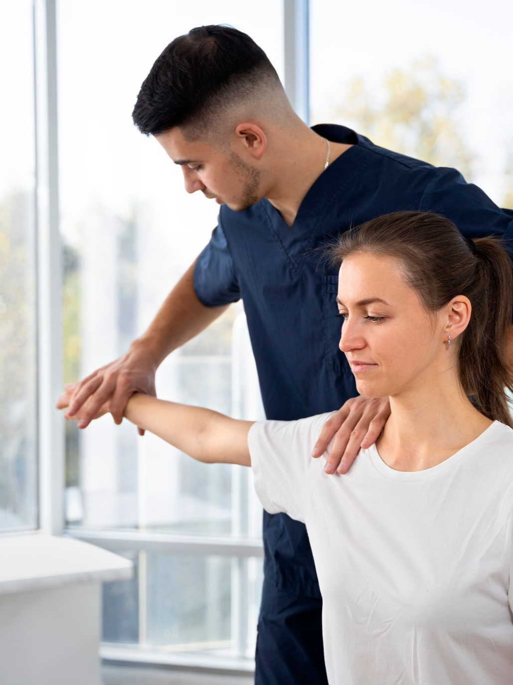 Physical therapist guiding a woman’s arm stretch in a bright clinic