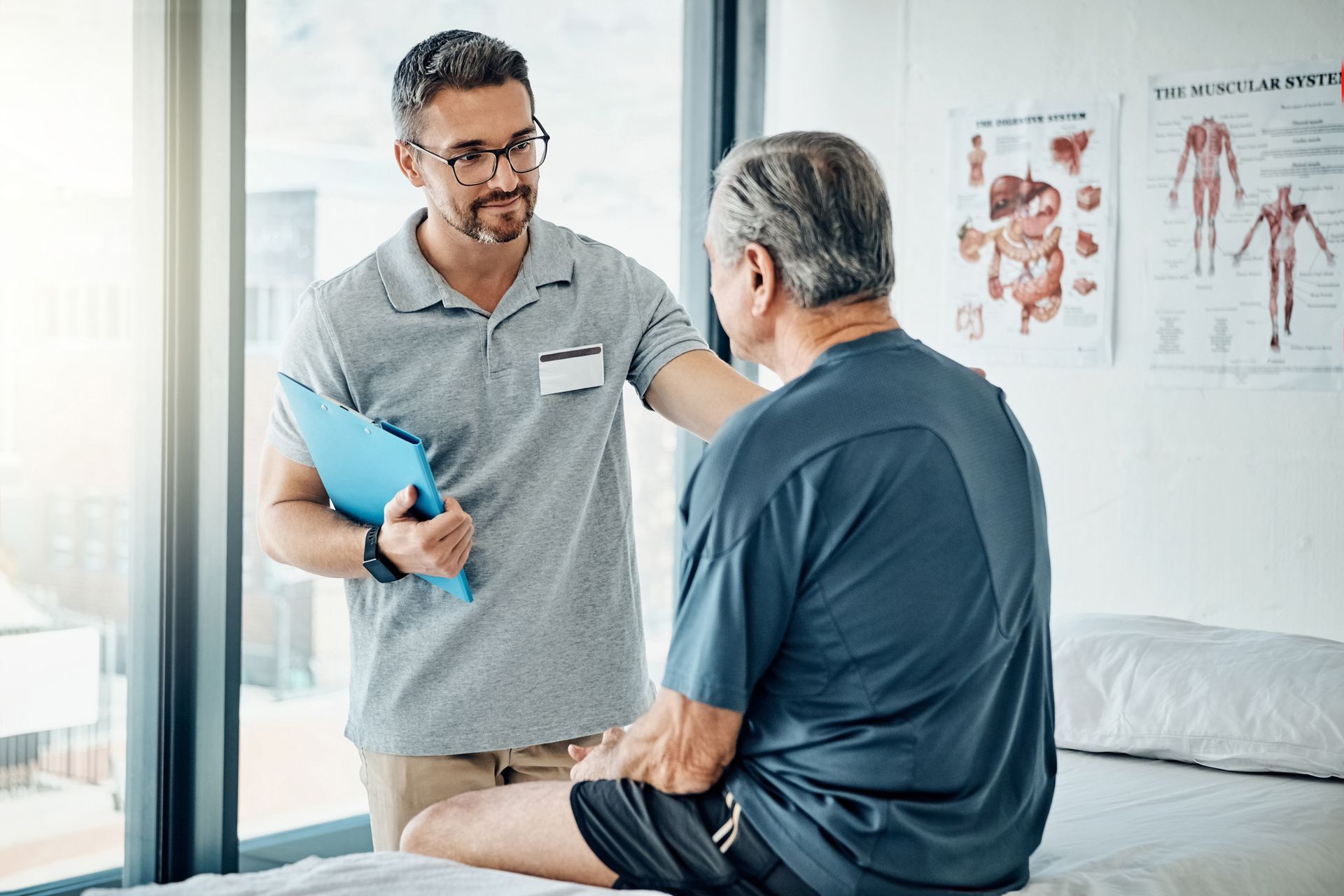 Doctor talking with seated patient in a bright clinic room, holding a blue folder