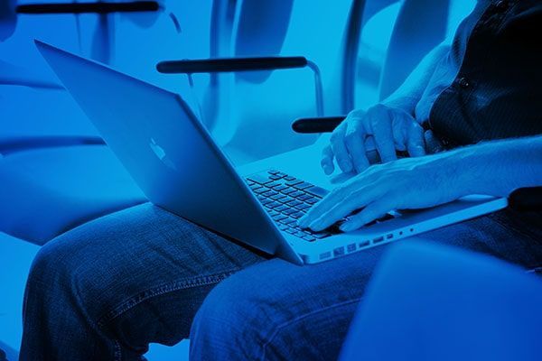 Person using a laptop on a couch in blue light