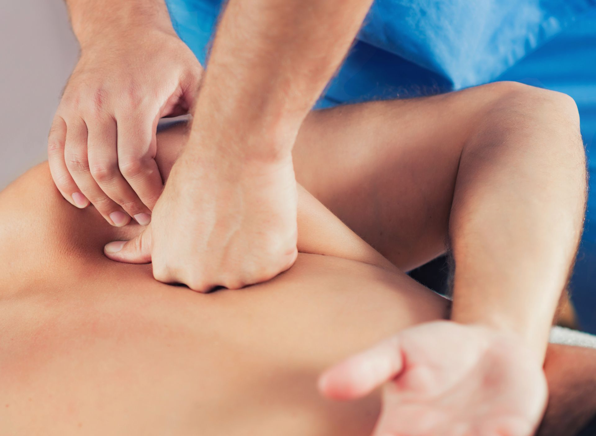 Hands giving a back massage on a person lying face down, with blue fabric visible nearby