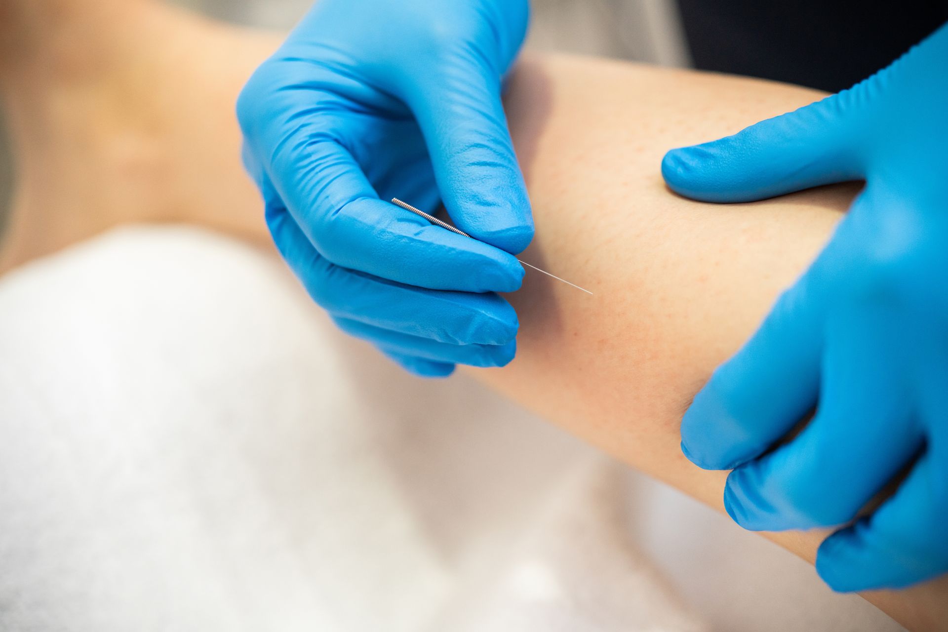 Gloved hands administering a small skin injection on a patient’s arm