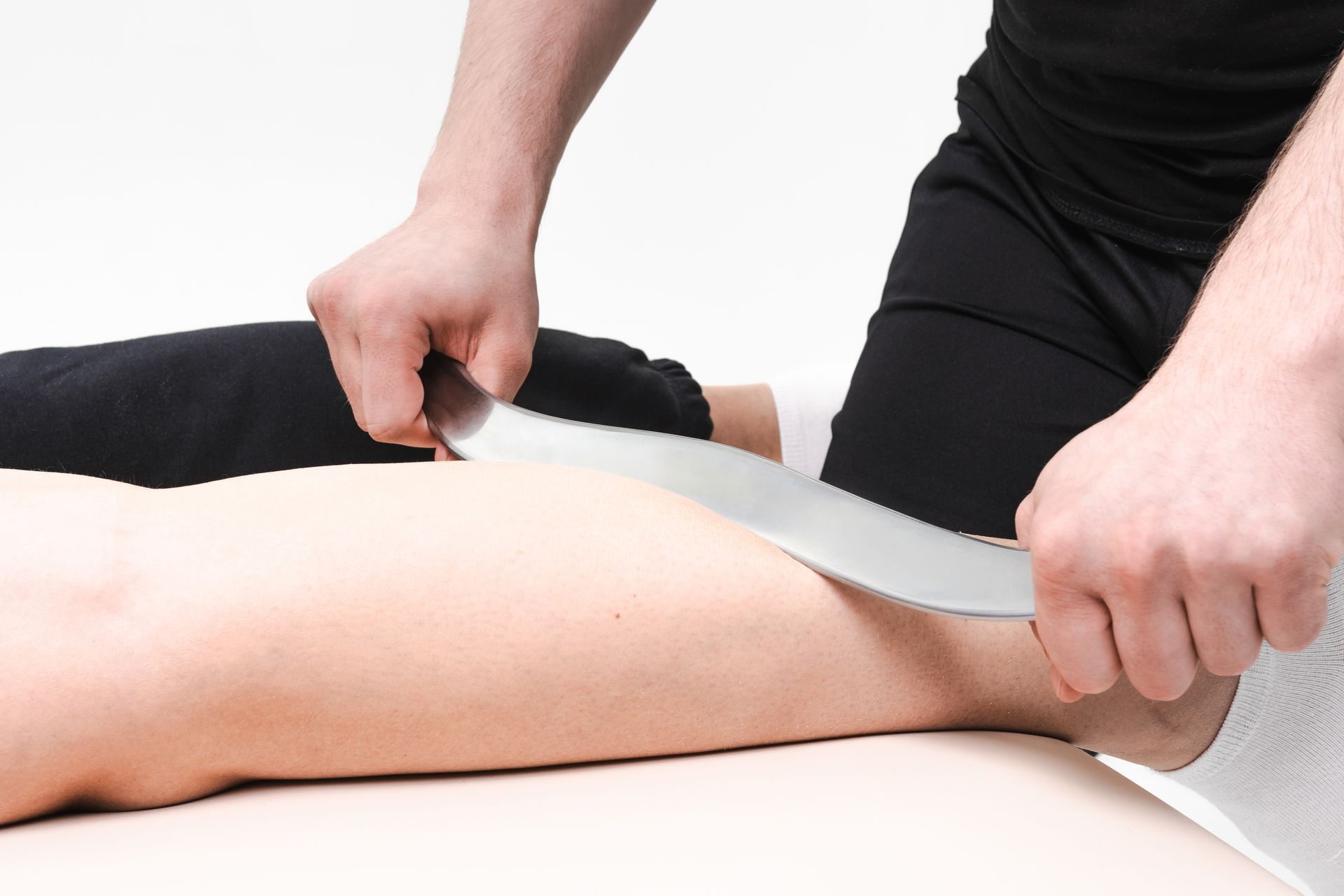 Massage therapist using a scraping tool on a person’s leg