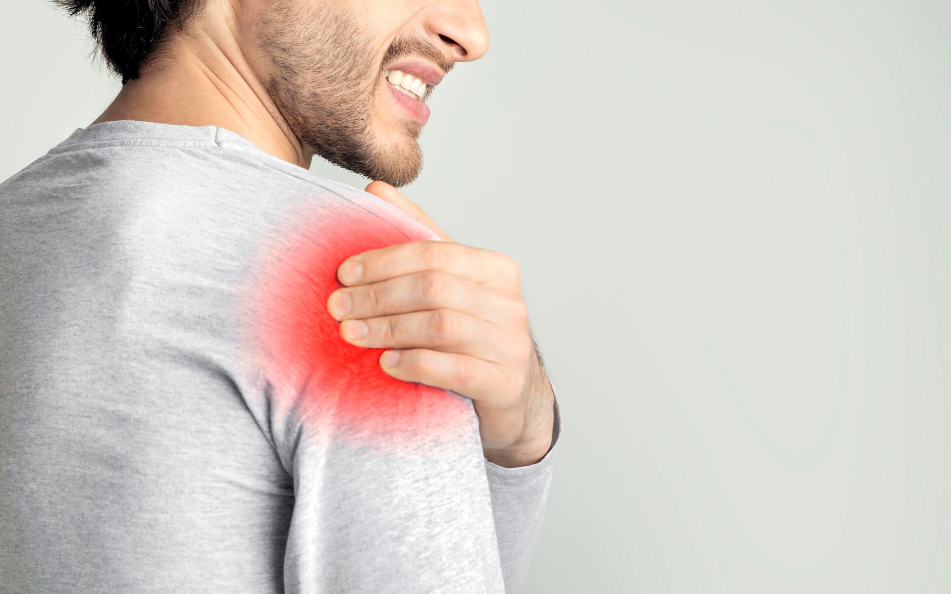 Man holding his shoulder with a red pain area highlighted