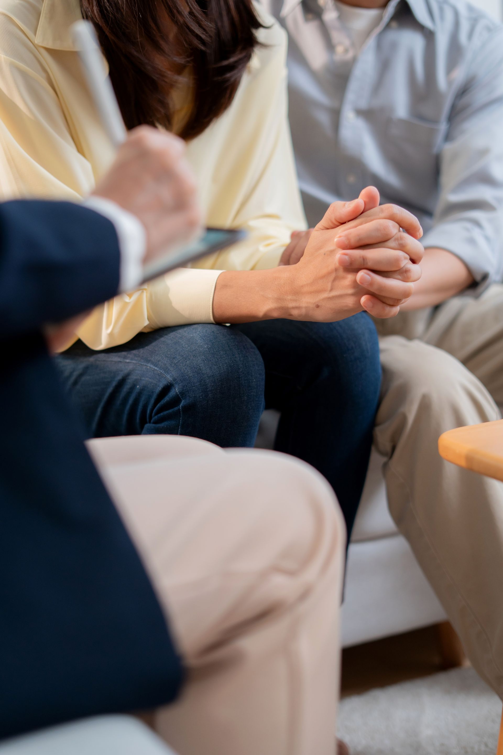 People seated in a counseling session, hands clasped in a supportive discussion