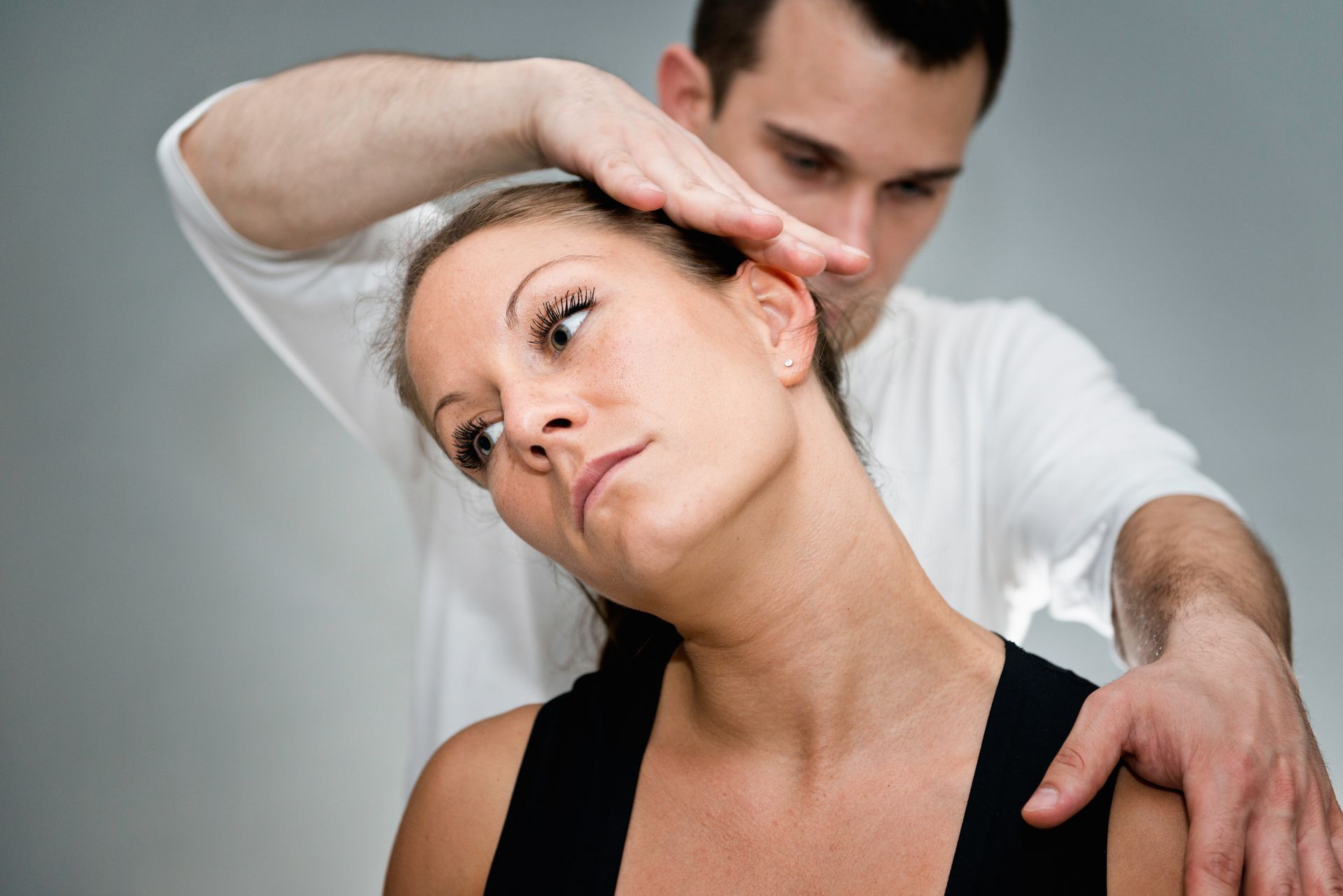 Physical therapist gently stretching a woman’s neck and shoulder in a clinic
