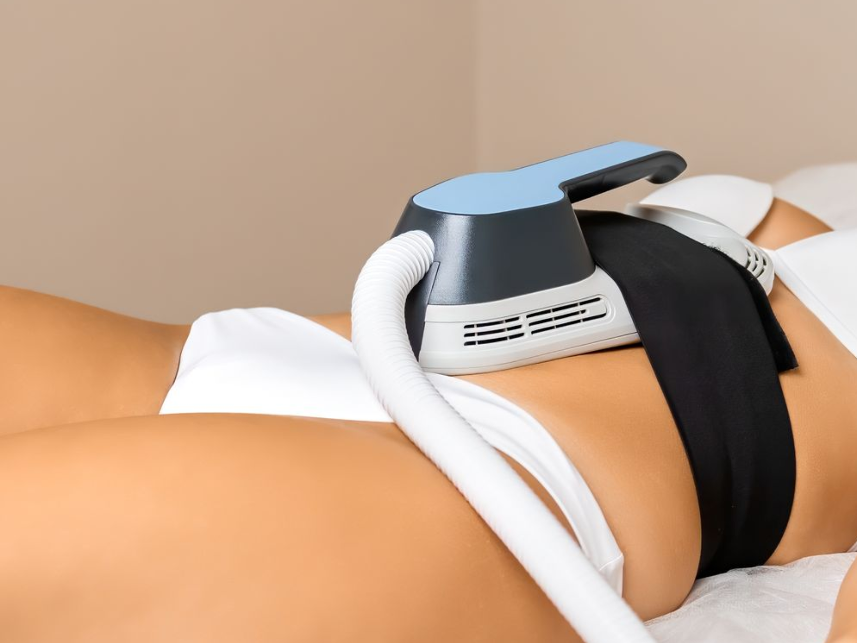 Person receiving body contouring treatment with a handheld device on the waist, close-up.