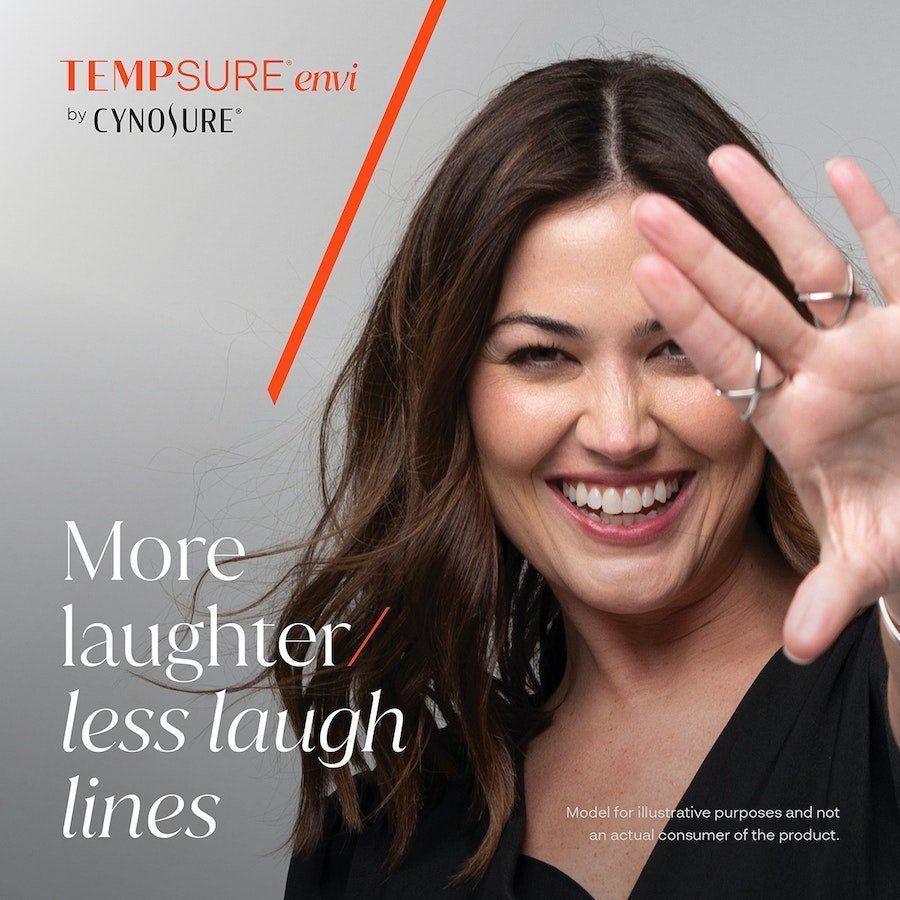 A woman is smiling and covering her face with her hand.