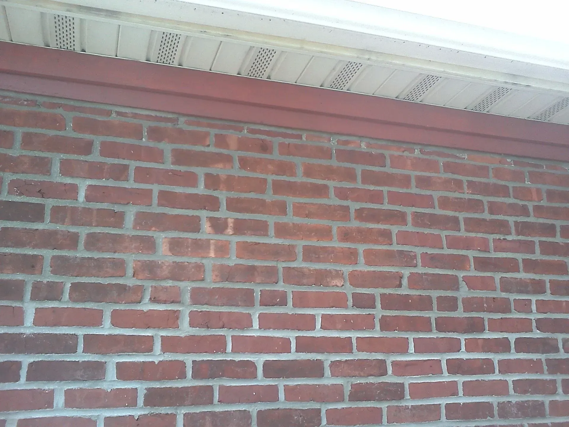 Brick wall with a red wooden trim under a white ceiling.