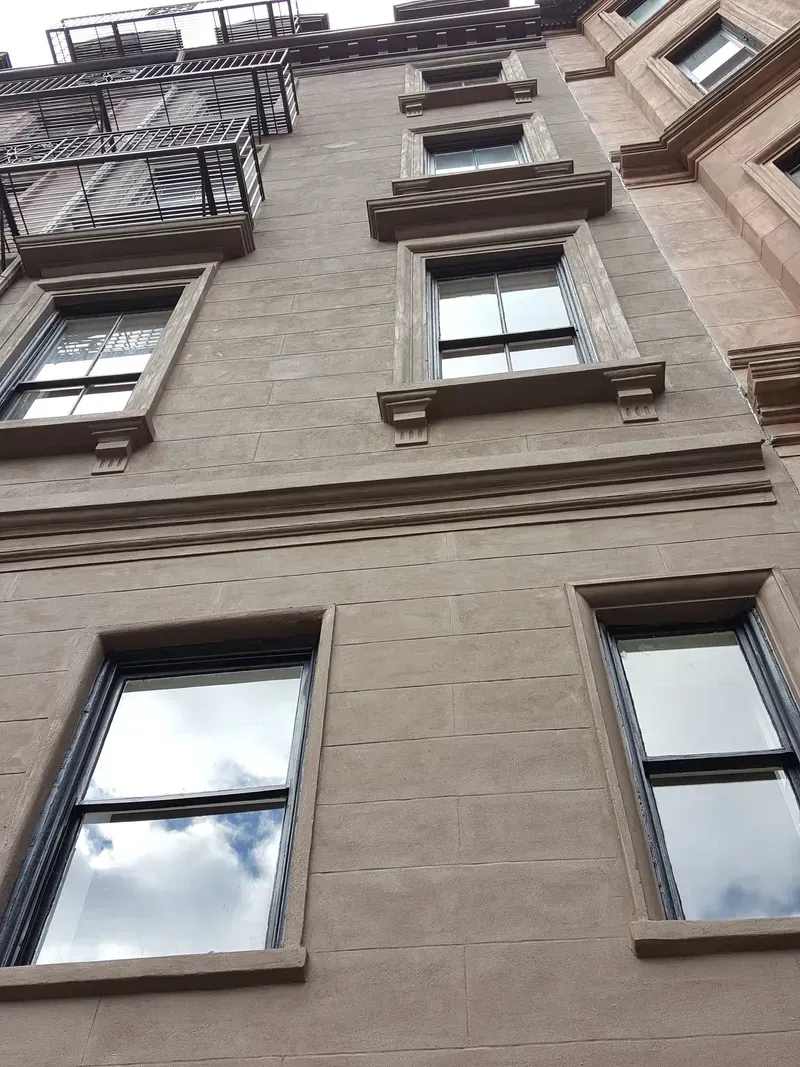 Brown brick building exterior with multiple windows, some with decorative trim.