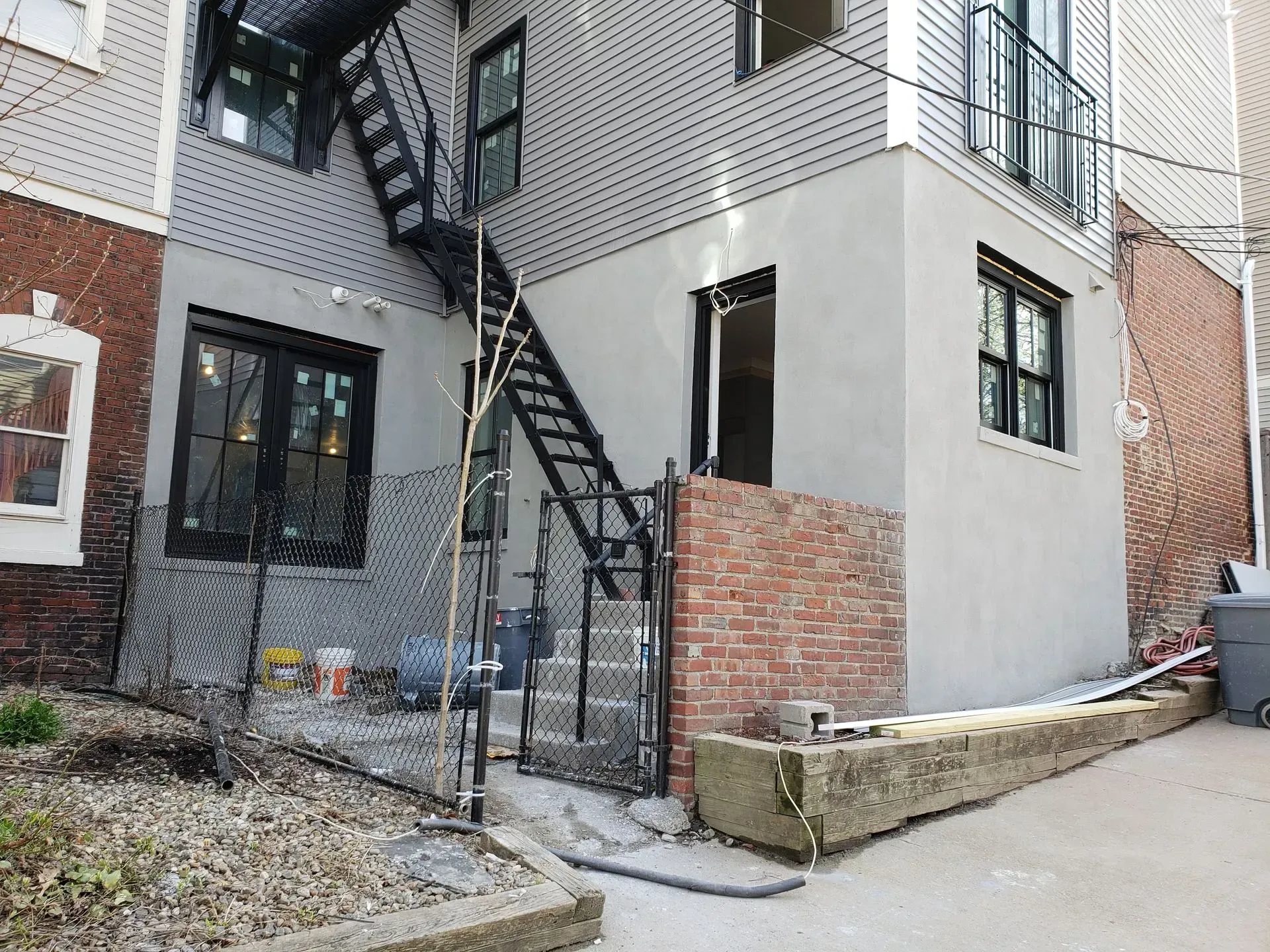 Back of a building with fire escape, brick wall section, and concrete work.