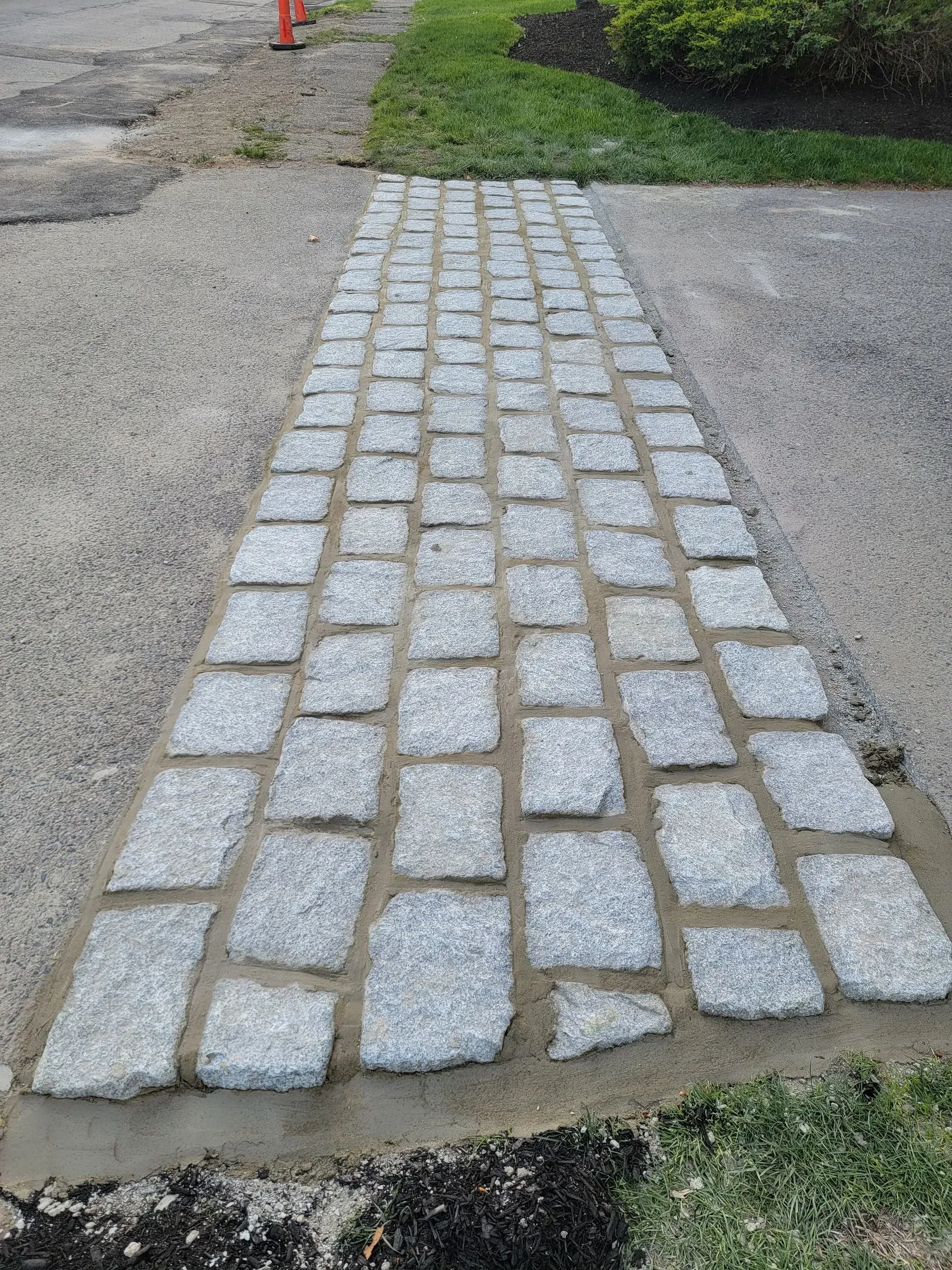 Granite cobblestone pathway leading through a gravel and grassy area.