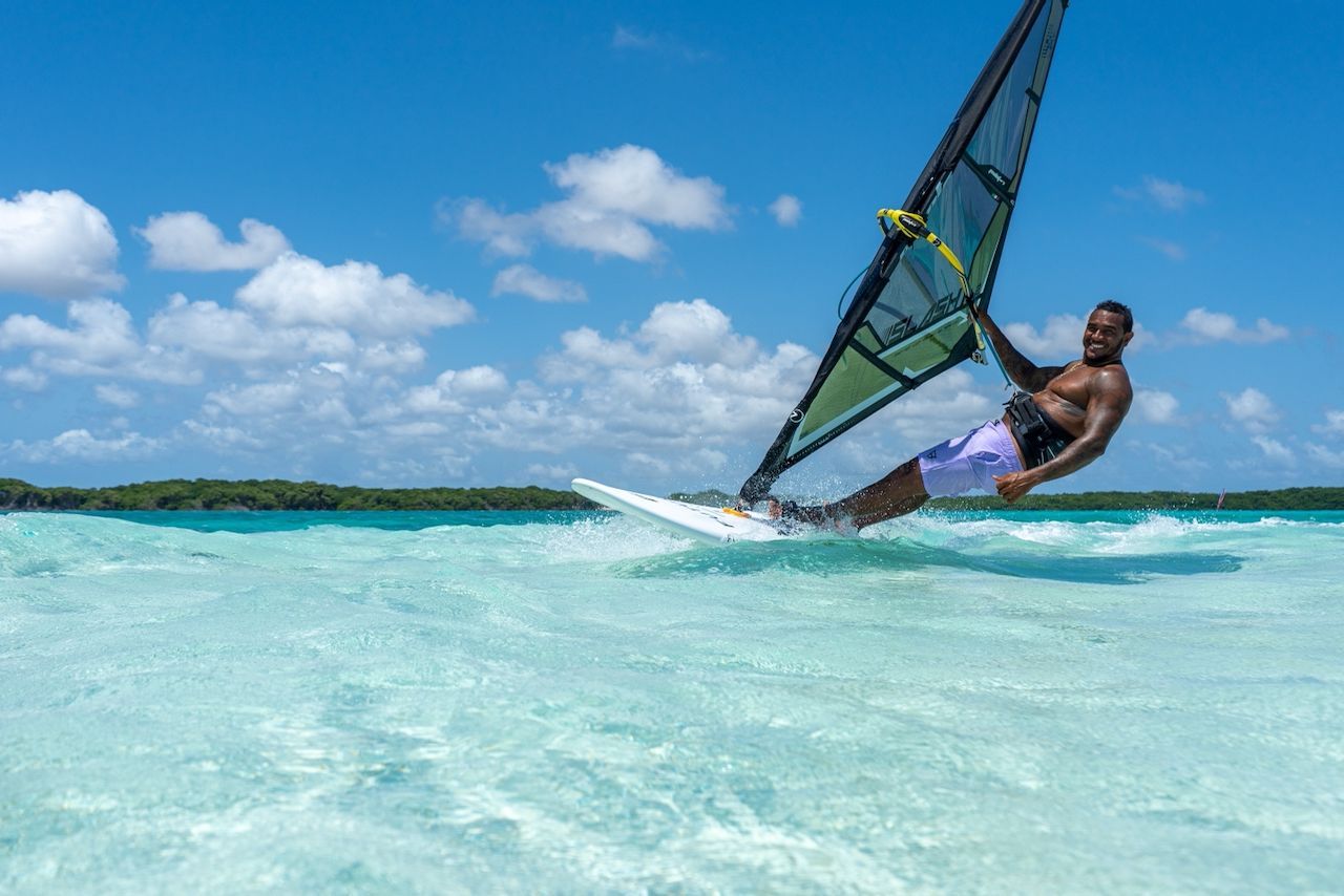 A man is windsurfing in the ocean on a sunny day.