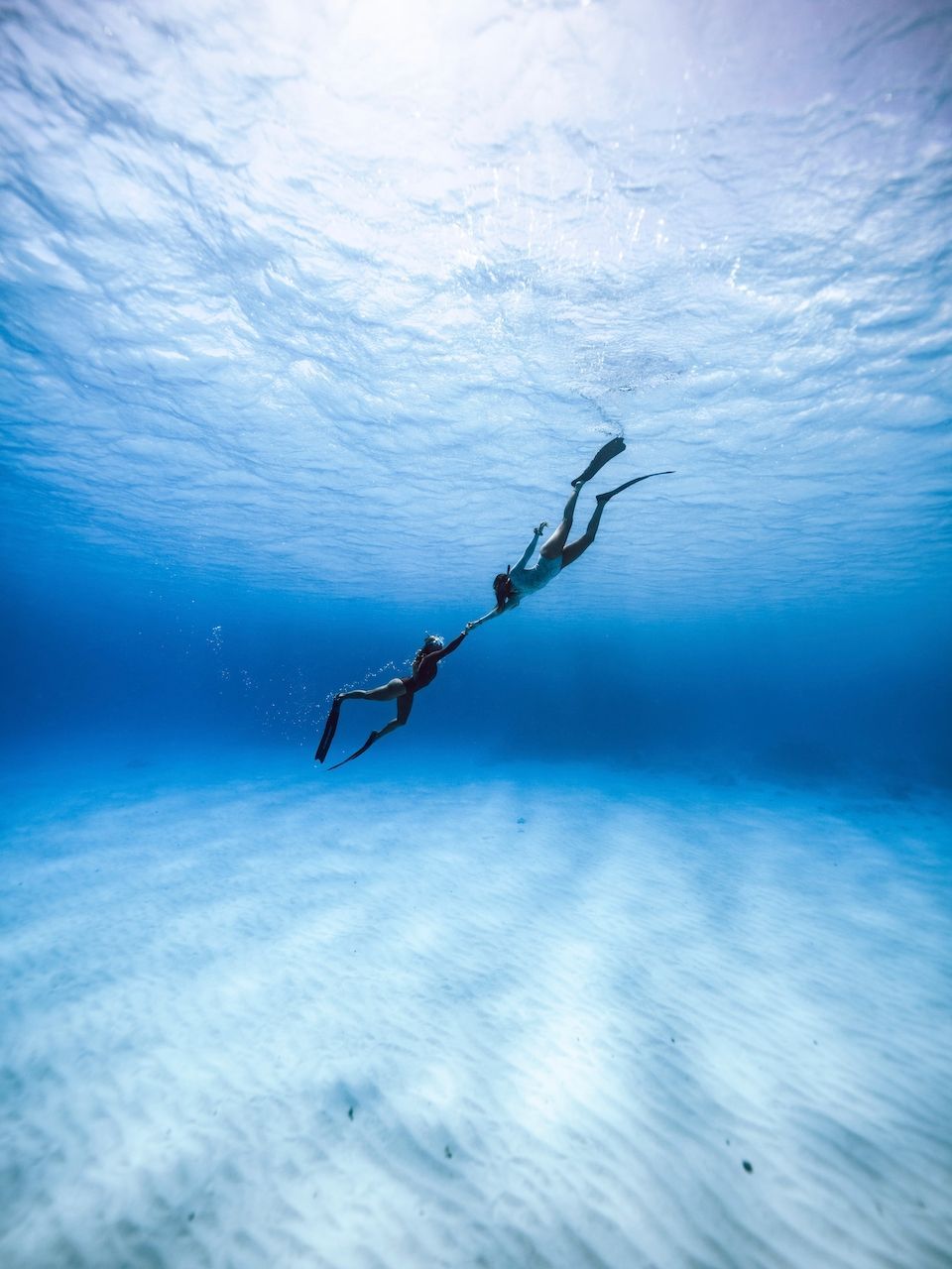 A couple of people are swimming underwater in the ocean.