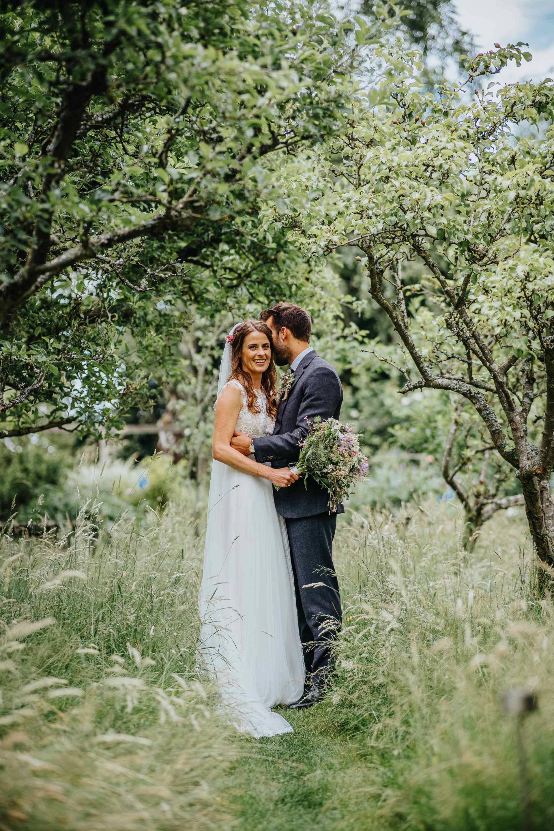 bride and groom on there wedding day walking from overgrown field at home gazebo wedding 