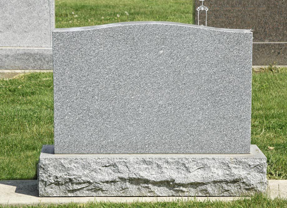 Una lapide è posta sull'erba in un cimitero.