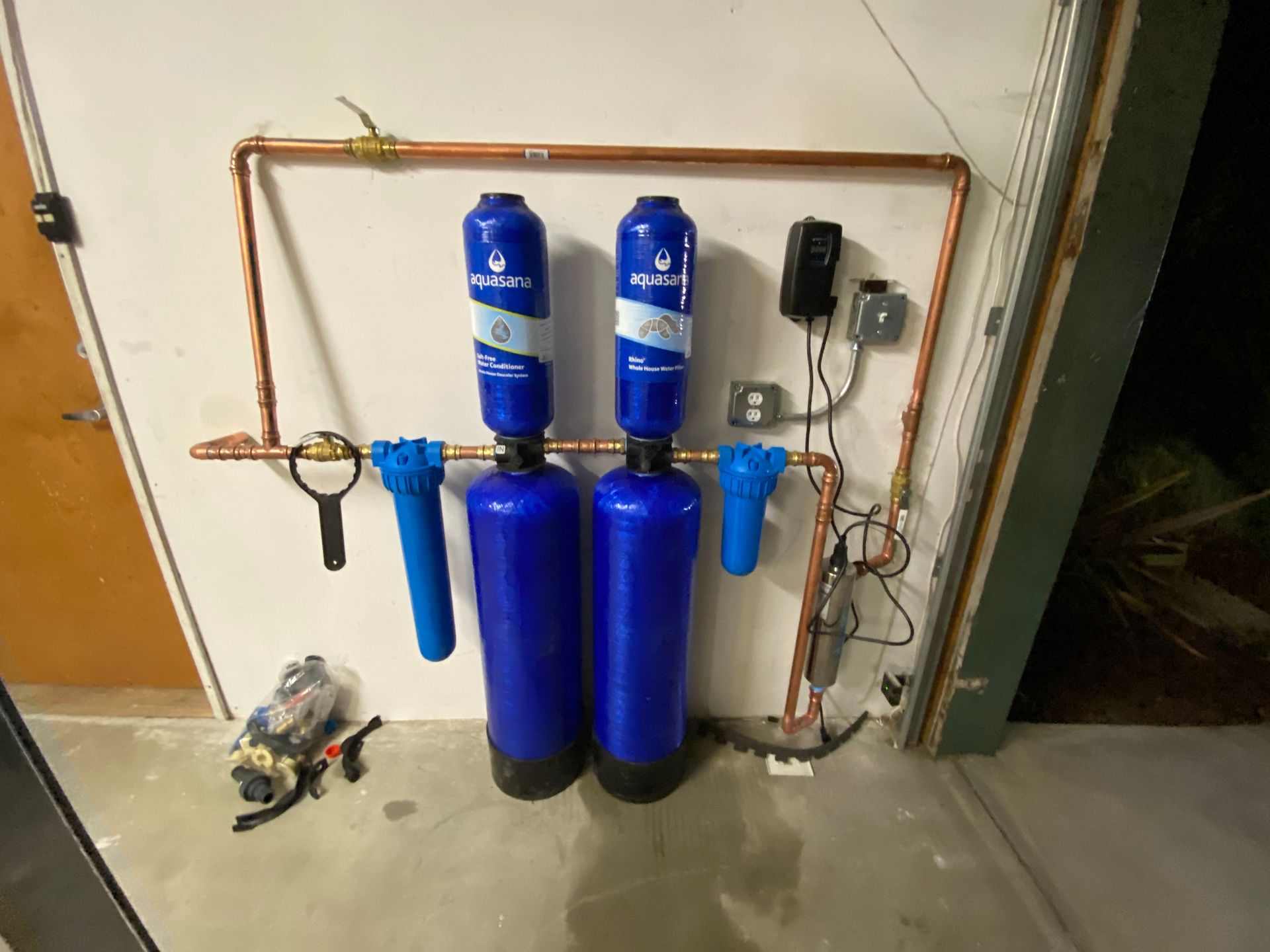 Two Blue Water Tanks Are Connected to A Copper Pipe on A Wall.