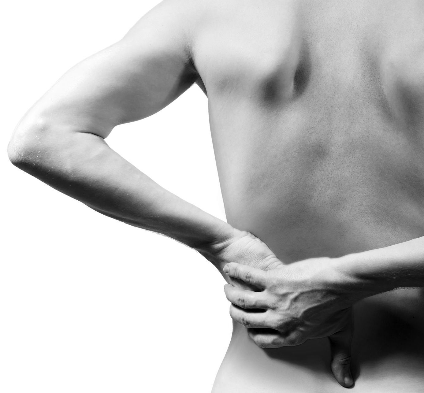 A person reaching back to hold their lower back in a gesture indicating pain or discomfort.