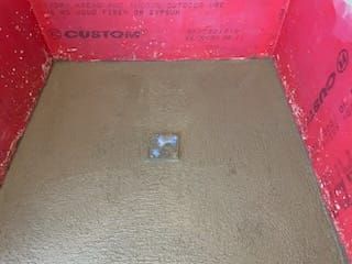 Shower floor with brown mortar, drain, and red waterproof walls.