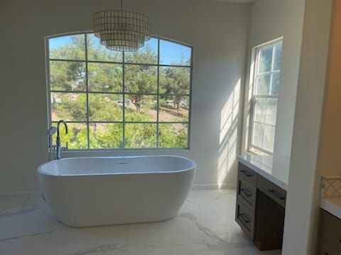 Bathroom with freestanding tub, large window overlooking trees, and dark wood vanity.