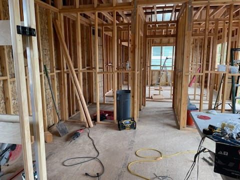 Interior of a building under construction, showing wooden framing and scattered tools.