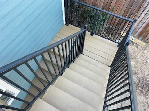 Staircase with black railings and composite decking. The stairs lead down to a platform.