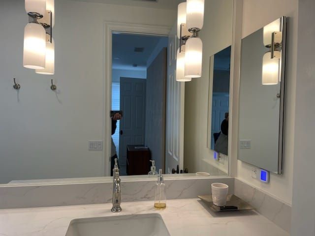 Bathroom vanity with large mirror, pendant lights, and sink.