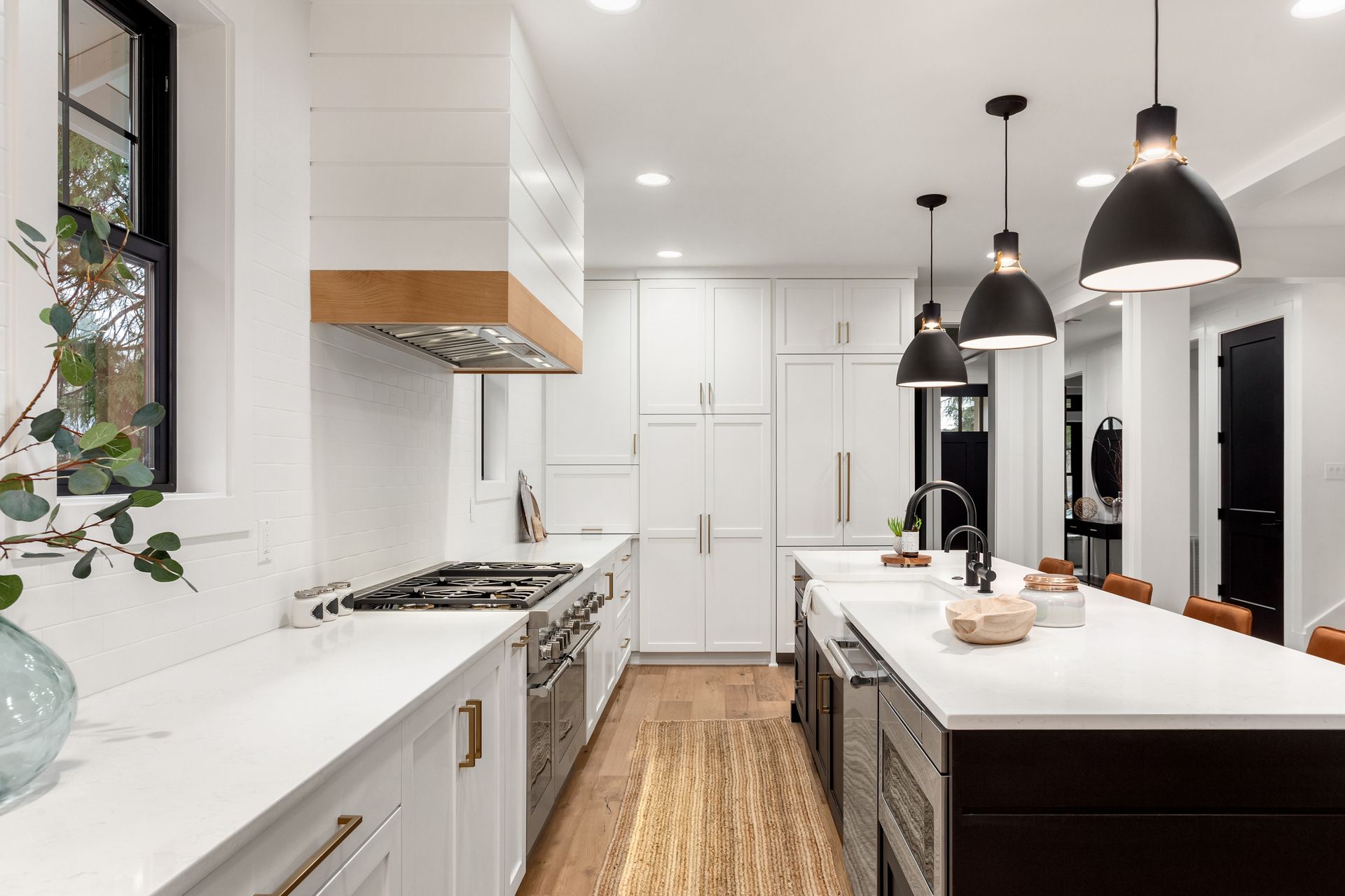 Bright modern white kitchen with island, pendant lights, gas range, and woven runner rug