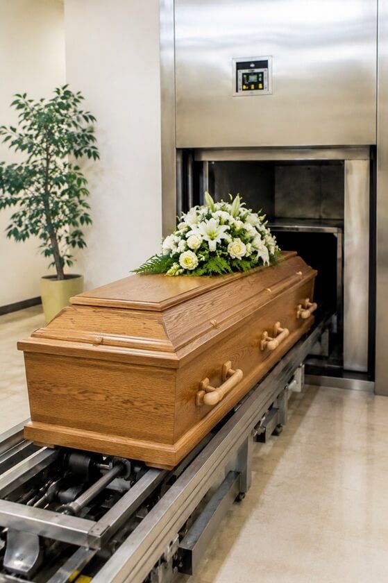 a somber room with a wooden casket entering a cremation chamber in West Allis, WI