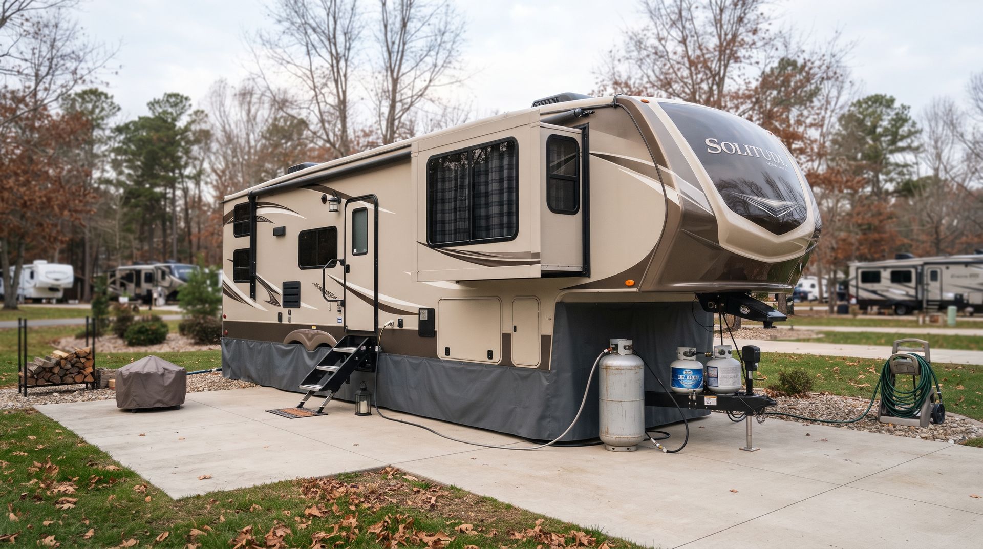 Beige RV parked on a concrete pad in a wooded campground, with slide-out extended and outdoor steps down.