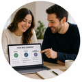 Two coworkers smiling at a laptop displaying a team strategy dashboard in a bright office
