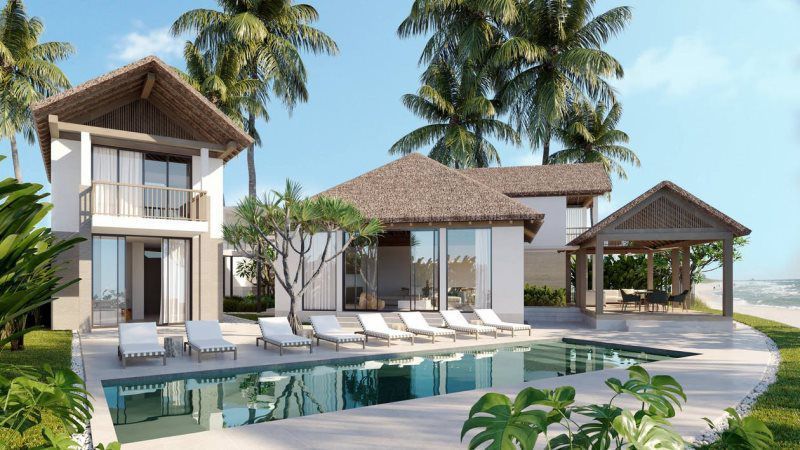 Luxury beachfront villa with pool, lounge chairs, and palm trees under a clear blue sky