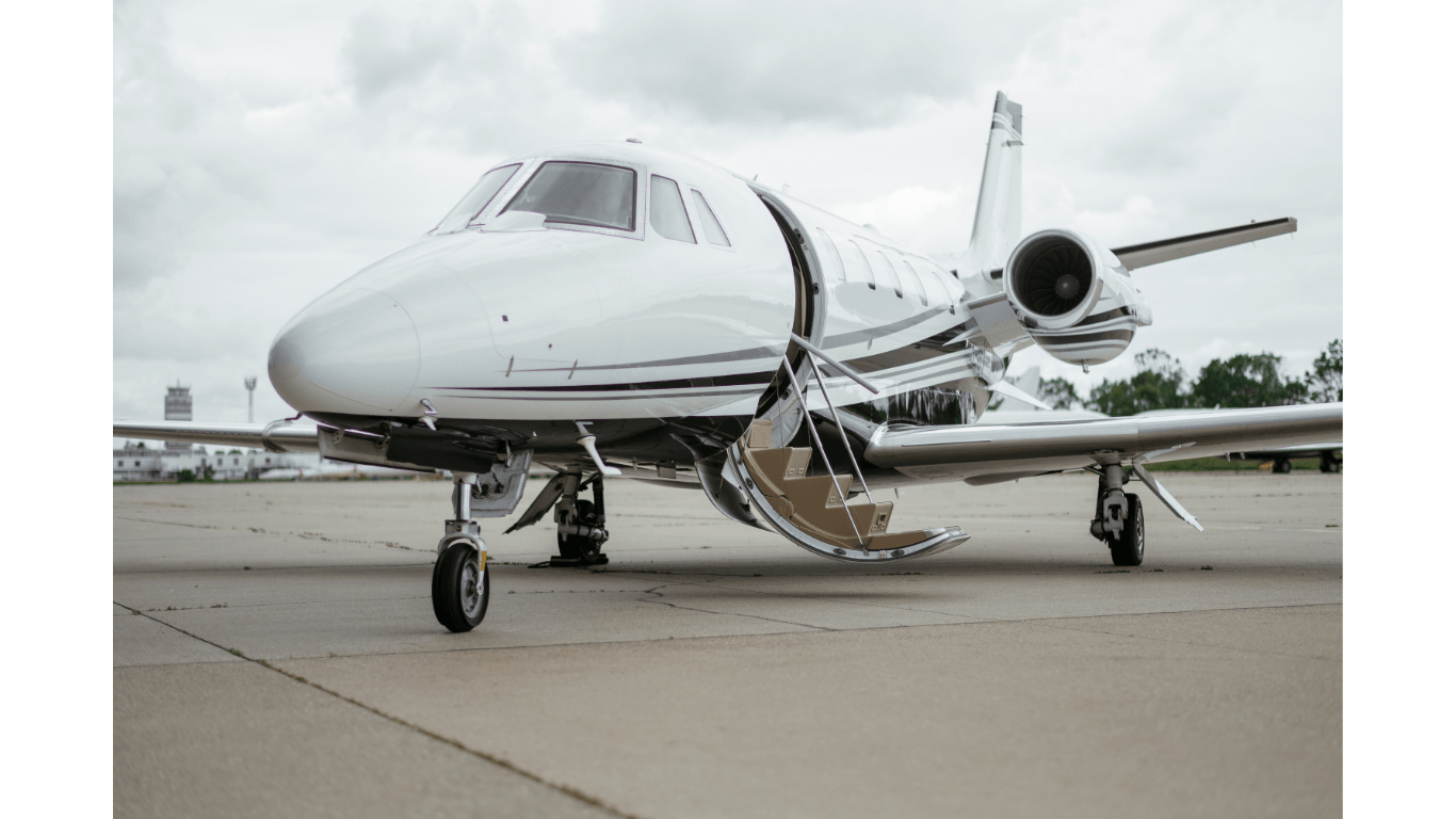 Silver private jet with open door on a runway.