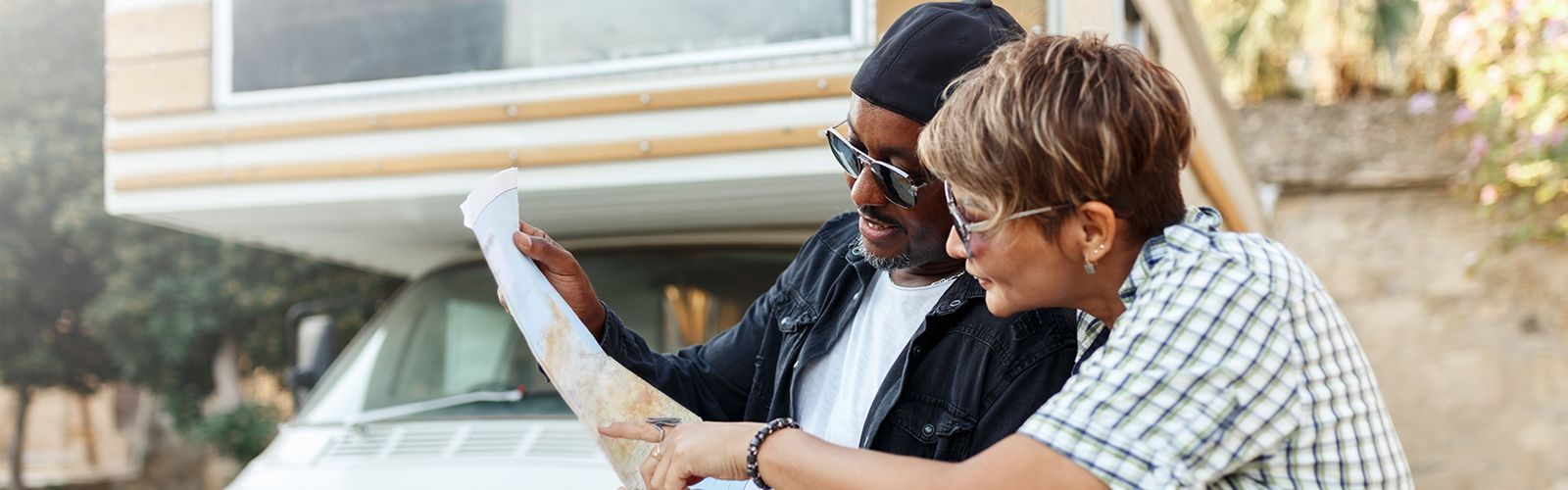 couple planning their route on a map outside an RV