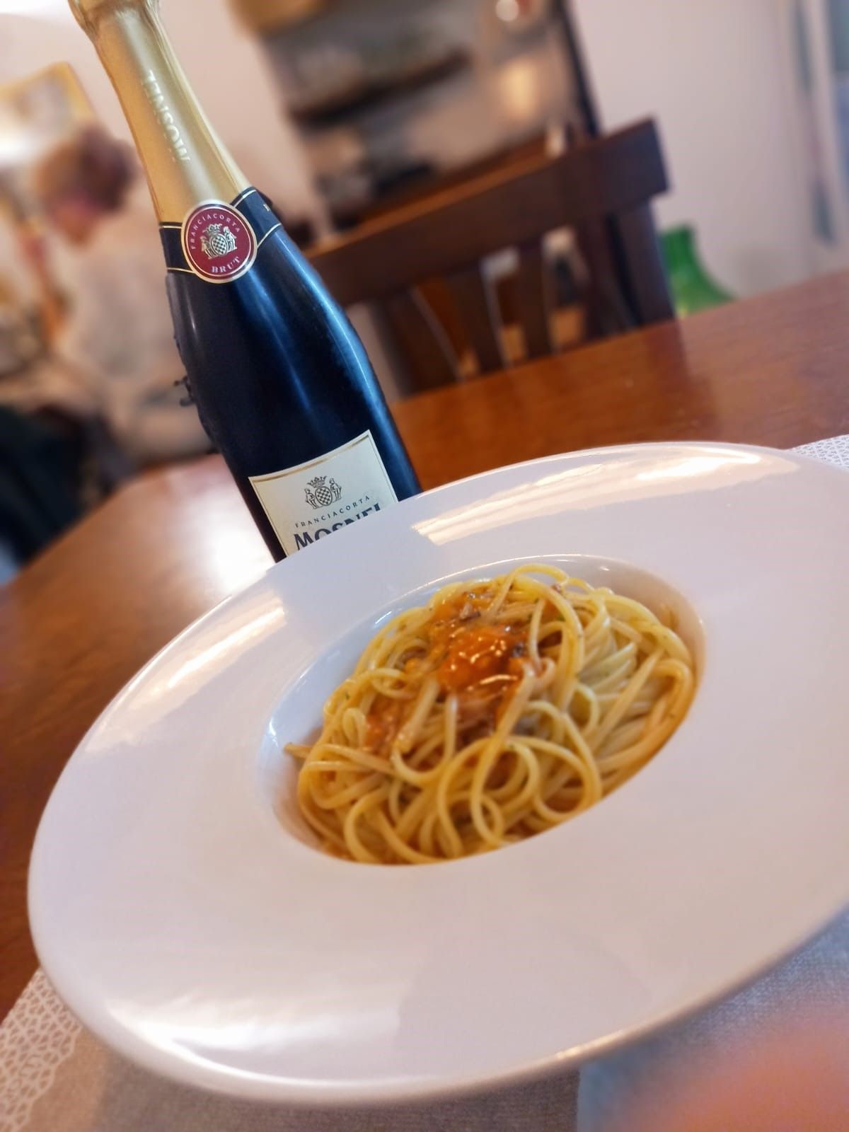 Un piatto di spaghetti accanto a una bottiglia di vino