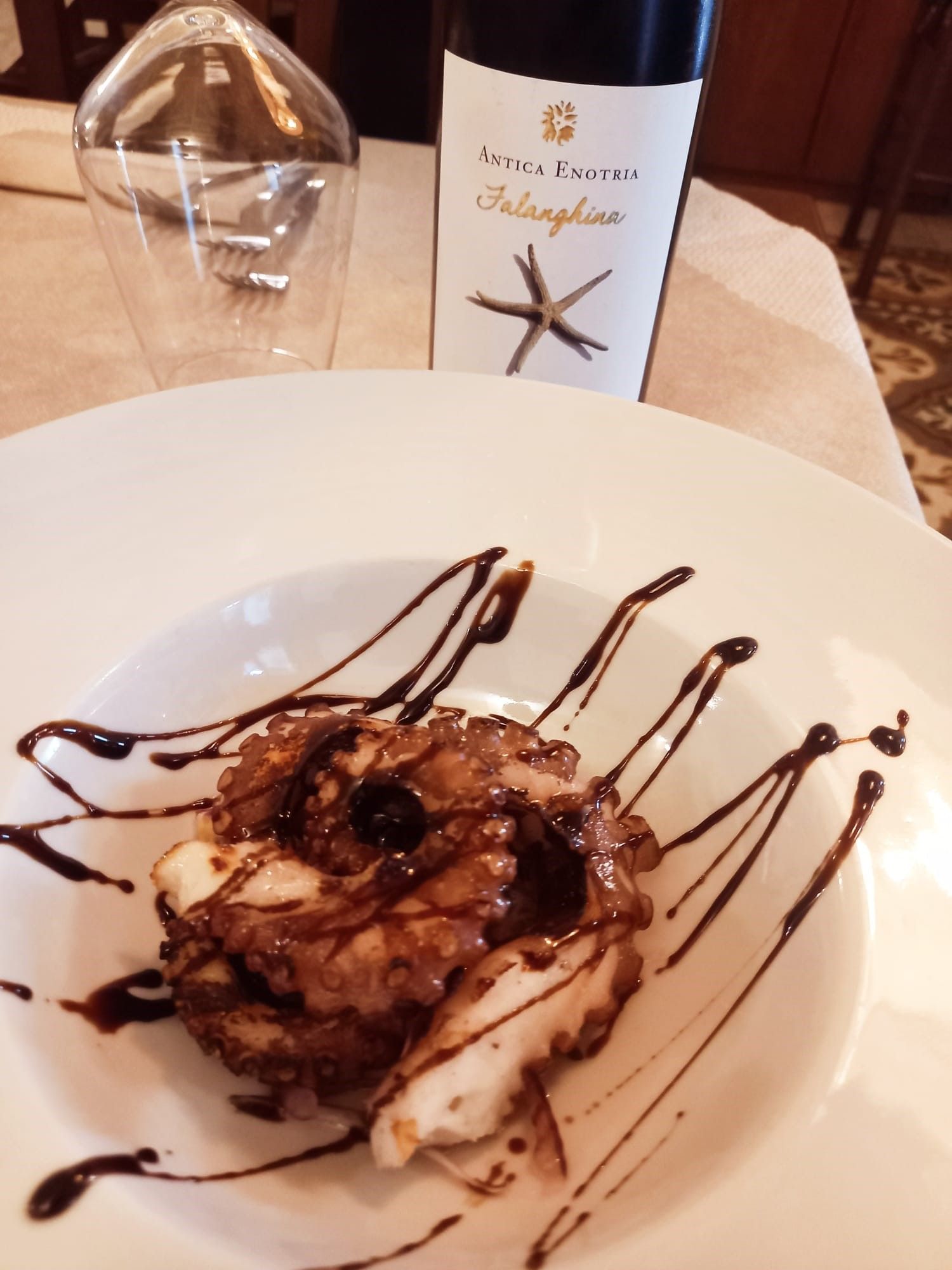 Una bottiglia di vino è posta accanto a un piatto di cibo